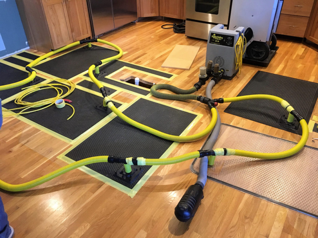 Air movers and drying mats placed on a hardwood floor